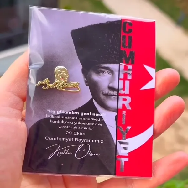 Atatürk portreli “Cumhuriyet Bayramımız Kutlu Olsun” kartına iliştirilmiş altın renkli Atatürk imzalı rozet